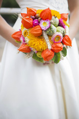 Blonde bride in white wedding dress holding bouquet and smiling