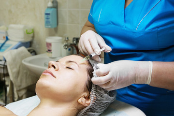 Obraz na płótnie Canvas Beautician performs a needle mesotherapy treatment on a woman face