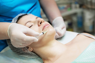 Obraz na płótnie Canvas Beautician performs a needle mesotherapy treatment on a woman face