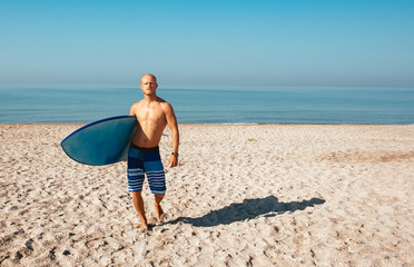 Surfer is going to surf in the ocean in a sunny day