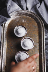three muffin with white powdered sugar on vintage yellow silver tray close-up