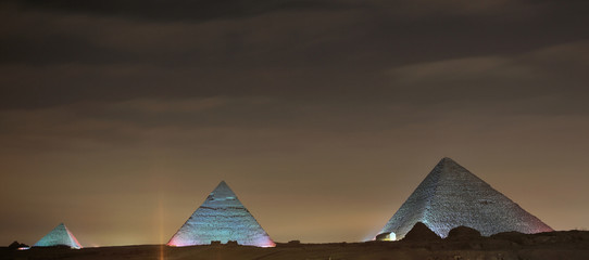 Naklejka na ściany i meble Dramatic sunset behind distant Egyptian pyramids in Giza, Cairo, Egypt 