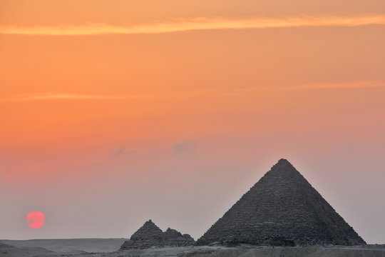 Dramatic sunset behind distant Egyptian pyramids in Giza, Cairo, Egypt 