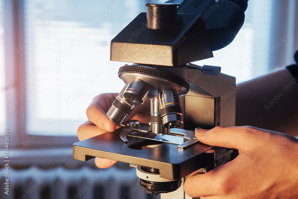 Poster close-up of scientist hands with microscope, examining samples.