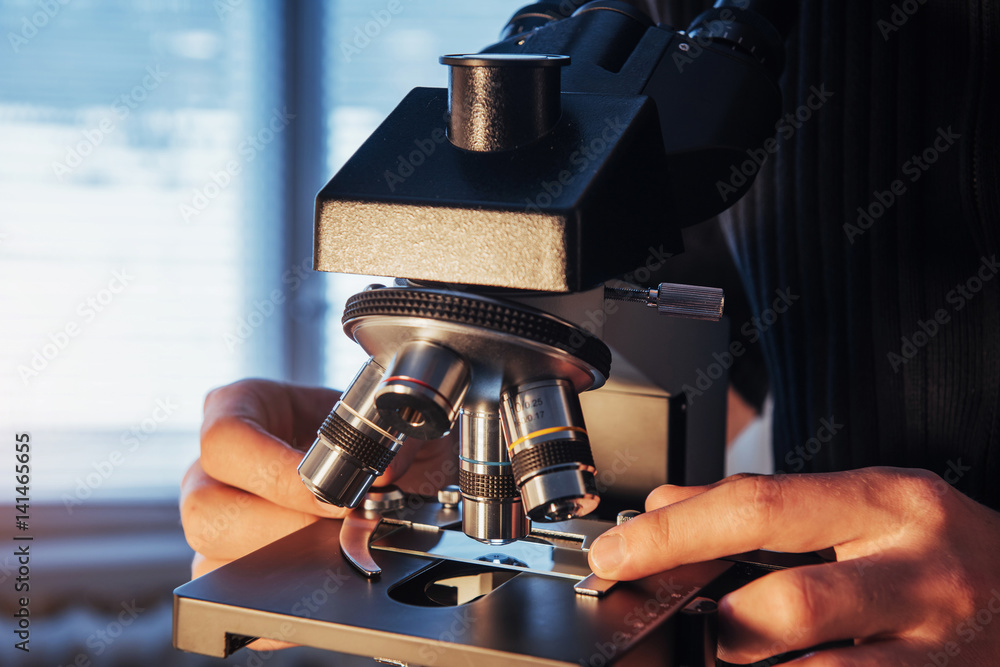 Poster close-up of scientist hands with microscope, examining samples.