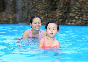 Fototapeta na wymiar Pretty little girl with her mother in swimming pool outdoors
