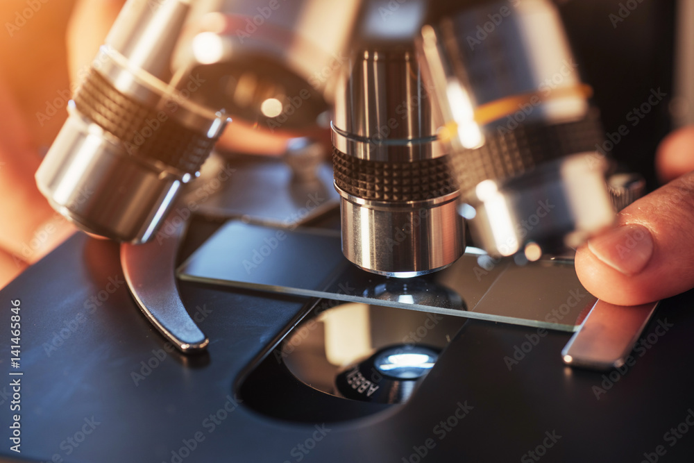 Poster close-up of scientist hands with microscope, examining samples.