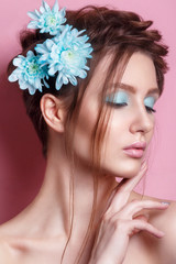 Naklejka premium Portrait of romantic young woman with blue flower looking at camera on blue background. Spring fashion photo. Inspiration of spring and summer. Perfume, cosmetics concept. 