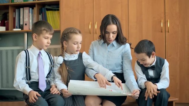 Elementary school pupil and teacher discussing picture with classmates