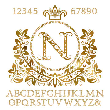 Golden patterned letters and numbers with initial monogram in coat of arms form. Shining font and elements kit for logo design.