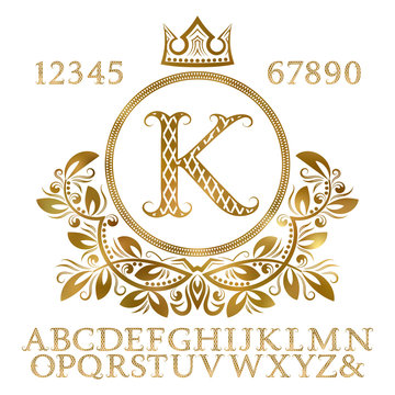 Golden patterned letters and numbers with initial monogram in coat of arms form. Shining font and elements kit for logo design.