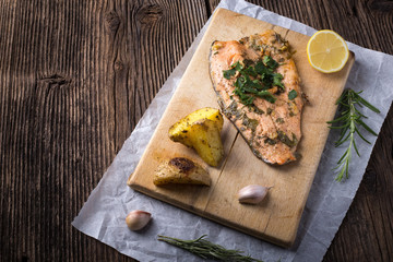 Trout with potateos on wooden board.