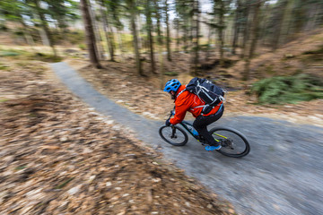 Fototapeta premium Mountain biker riding on bike in early spring mountains forest landscape. Man cycling MTB enduro flow trail track. Outdoor sport activity.