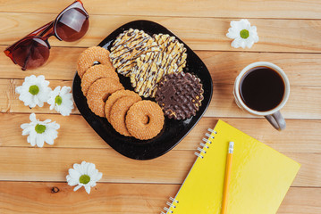 Coffee espresso stands on a wooden table with cookies, pad and pencil.