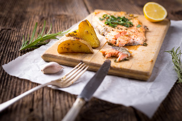 Trout with potateos on wooden board.
