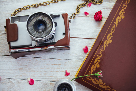 Retro camera roll photo film and flowers on white wooden background