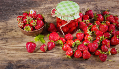 Fresh red strawberry and jam on wood background