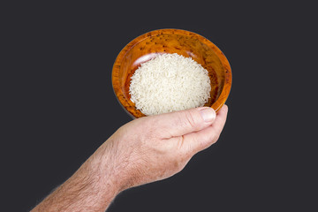 Hand holding wooden bowl with rice