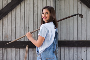 Portrait of young female farmer holding a rake over the shoulder
