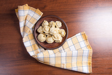 Boiled Ukrainian meat dumplings or ravioli on wooden background.