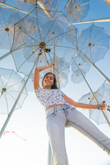 Girl holding an umbrella. Installation Flying umbrellas, Greece. Group of umbrellas on blue sky...