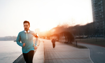 Handsome runner exercising by running in city