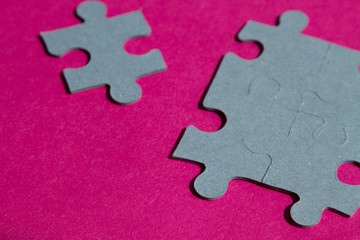 Jigsaw puzzle pieces on bright pink background, horizontal