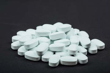 Medical white tablets or supplements for the treatment and health care on a black background