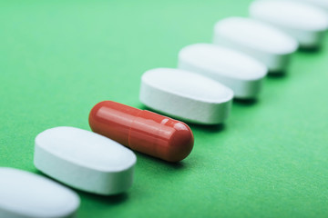 Medical white pills and brown capsules for the treatment and health care on a green background