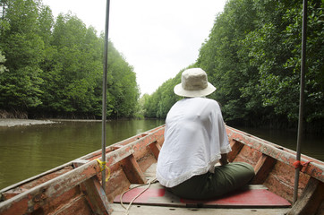 Traveller thai woman sit on service long tail boat for looking and travel view riverbank and Mangroves forest or Intertidal forest on river