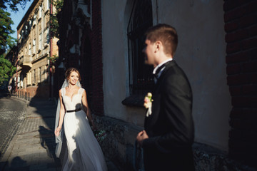Sun shines over stunning seductive bride walking to the groom along the street