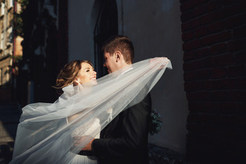 Bride whirls her veil around groom before she kisses him
