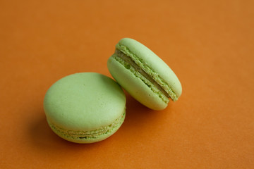 Pair of Green pistachio macaroons over orange background