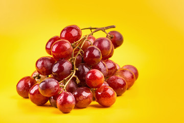 fresh and delicious red grapes isolated on yellow background