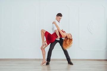 Young beautiful woman in a red dress and a man dancing, isolated on a white background.