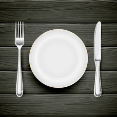 Plate with fork and knife on black wooden background