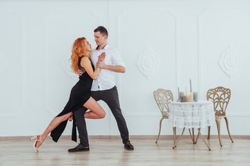Young beautiful woman in a black dress and a man in white shirt dancing.