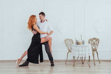 Young beautiful woman in a black dress and a man in white shirt dancing.