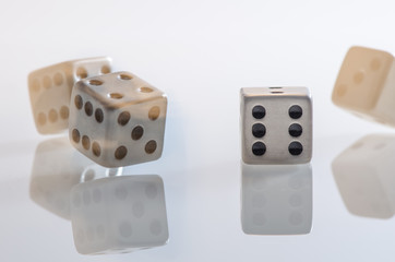 fallende Würfel aus Edelstahl auf weißer Glasplatte