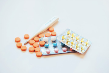 Flu. Thermometer with elevated temperature and many pills on light background