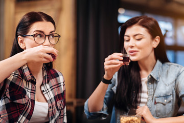 Close up of delighted girls while drinking liqueur