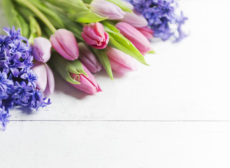 Beautiful pink tulips and hyacinths on white-plank background 