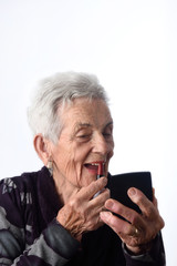 Old woman painting her lips on white background