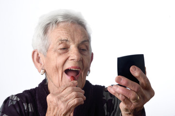 Old woman painting her lips on white background