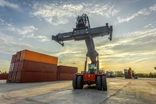 container stacker forklift standing-by for next lifting containers in yards with sunset in background