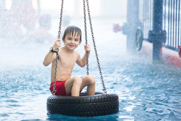 Sweet child, boy, playing in water world playground, enjoying attractions