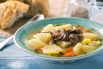 Potato soup with beef on wooden background.