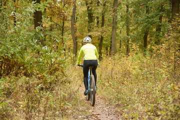 Obraz premium Female mountain biker. Rear view shot of a female cyclist out for a ride on her mountain bike in the forest.