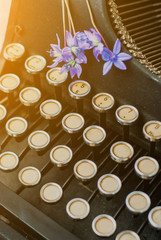 Old antique black vintage typewriter with blue romantic spring flowers