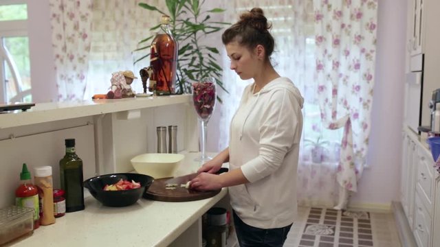 Young beautiful woman preparing a salad in the kitchen. Onions